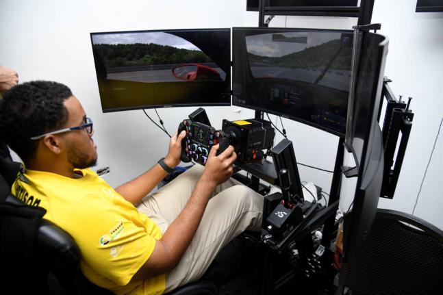 Jayden Harrison, professional simulation racer for S Hotel’s team Jamaica gives a demonstration of the driving simulation at a press conference at S Hotel yesterday. 