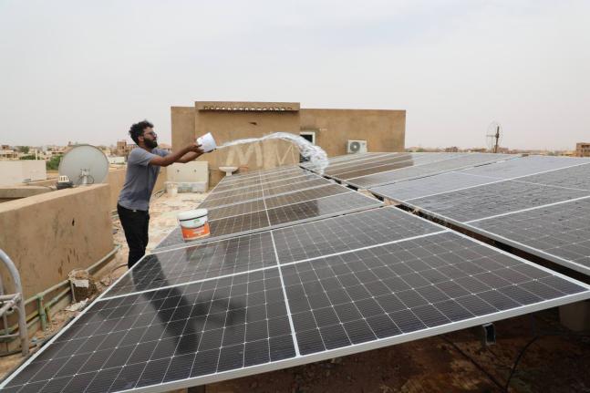 A technician cleans solar panels installed on the roof of a home in Omdurman, on the outskirts of Khartoum, Sudan.