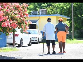 Eighty-five-year-old Winston Foster (left) braves the mid-morning sun to cast his ballot in St Catherine East Central.