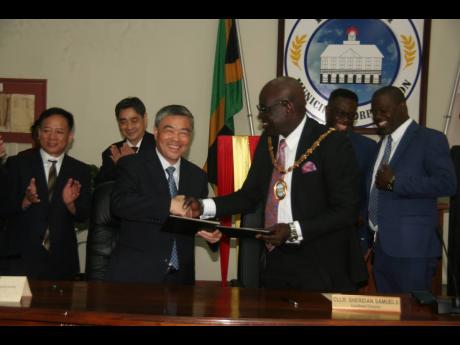 Lucea’s Mayor Sheridan Samuels (third right) and  Wang Bin (fourth right), vice-chairman of the Standing Committee of Huangshi  Municipal Congress of the People’s Republic of China, exchanging signed documents formalising the friendship deal between the Hanover Municipal Corporation and the Huangshi Municipal People’s Congress of China. Councillors and members of the visiting Chinese delegation look on.