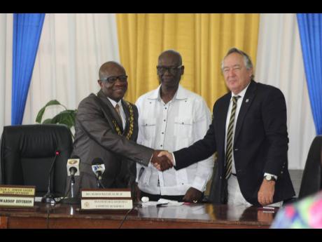Credit: Photo by Leon Jackson Burying the hatchet: Falmouth Mayor Collen Gager (left) and Trelawny Custos Paul Muschett shake hands as they pledged yesterday to work together for the better of the parish. Looking on is Local Government Minister Desmond McKenzie.