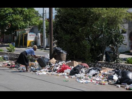 An elderly woman disposes of garbage from her household on Collie Smith Drive In Jones Town, Kingston. Some residents voiced sanitation concerns while others were irritated by people’s disregard for the environment. 