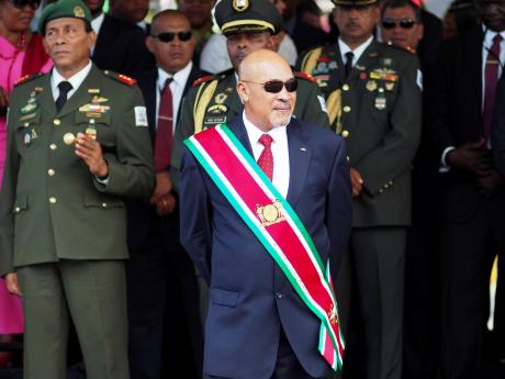 In this August 12, 2015, photo, Suriname President Desire Bouterse observes a military parade after being sworn in for his second term. A Suriname court convicted Bouterse on Friday for his role in the 1982 killings of 15 political opponents. 