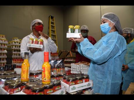 Albert Bailey (left), CEO, Spur Tree Spices, shows off a range of products that the company produces to Guillen Grillo (right), Costa Rican chargé d’affaires to Jamaica, during a tour of the factory yesterday. Mohan Jagnarine (centre) executive director