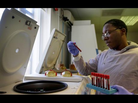 Credit: AP Leon McFarlane, a research technician, uses a centrifuge on blood samples from volunteers in the laboratory at Imperial College in London, Thursday, July 30, 2020. Imperial College is working on the development of a COVID-19 vaccine.