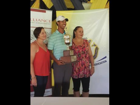 Khristian Chin (centre), 2019 champion of the Lindy Delapenha Golf Classic, is presented with the trophy by Delapenha’s daughters Marie Claire (left) and Linda.