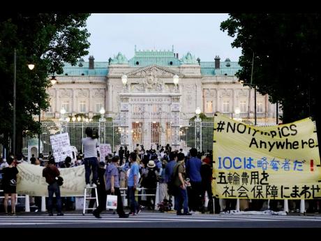 Protesters against the Tokyo Olympics gather outside Akasaka Palace, a Japanese state guest house, where the welcome party for IOC President Thomas Bach and its officials were held in Tokyo yesterday. The banner at right  reads 'IOC is a looter! Use Olymp