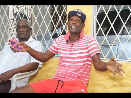 Clayton Boothe (right) and his father, Clinton, of Longwood, Clarendon, share fears of the gully that runs through their yard. It is believed that Dennis Jackson, 78, was washed away when he attempted to cross the flooded roadway on his way back home Frida