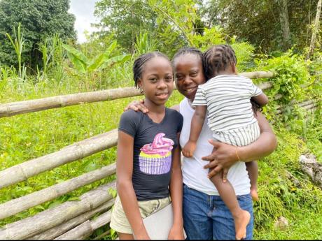 Coniesea McFarlane stands with her mom, Marcia Martin, and Coneile McFarlane in the area they receive good data service to log in to online classes.