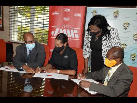 Shani Duncan-Falconer (seated, centre), senior corporate manager, JMMB Group SME Resource Centre and Professor Colin Gyles, actg. president, University of Technology, Jamaica sign a Memorandum of Understanding (MOU) between the two institutions at the JMMB