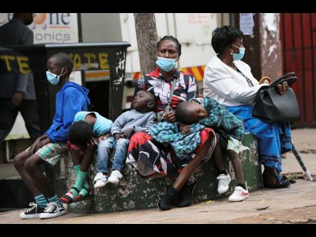 Credit: AP A mother takes time to rest with her children in Harare, Zimbabwe on Friday. A slew of nations have moved to stop air travel from southern Africa, and stocks have plunged in Asia and Europe in reaction to news of a new, potentially more transmissible COVID