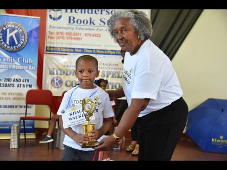 Nest Nursery and Preparatory School’s Khalil Walker, the second place and champion boy winner of the Kiwanis Club of Providence Montego Bay Kiddie Bee Spelling Competition collects his trophy from Kiwanian Joy Ford. 