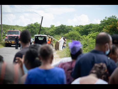 Residents of Seaview Gardens look on as members of the Jamaica Constabulary Force, the Jamaica Fire Brigade and morgue attendants retrieve the body of correctional officer Shannon Briscoe from a gully in Seaview Gardens, St Andrew, last Saturday.