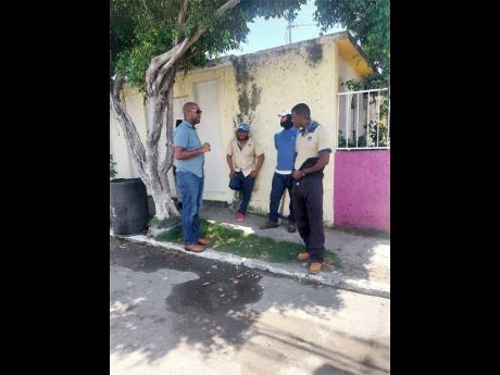 St Catherine South Eastern Member of Parliament Robert Miller speaks with National Water Commission crewmen who were in Falmouth East, Waterford, Thursday. Clogged manholes have worsened sewerage woes in the community.