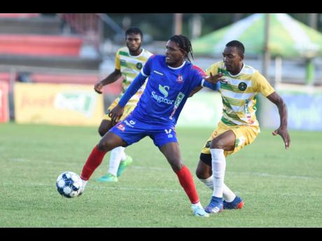 Stephen Barnett (left) of Dunbeholden shields the ball from Kenroy Lumthen of Vere during their Jamaica Premier League (JPL) match at Anthony Spaulding Sports Complex today. Dunbeholden won 1-0.
