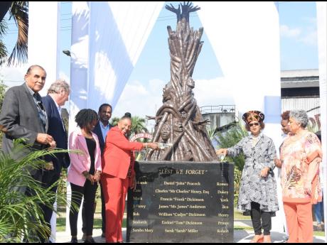 Culture Minister Olivia Grange (fifth left) and Professor Verene Shepherd (third right) paying tribute to the ancestors by pouring rum during a ceremony unveiling the slave monument ‘Lest We Forget’ at the Appleton Estate in St Elizabeth on Monday. Als