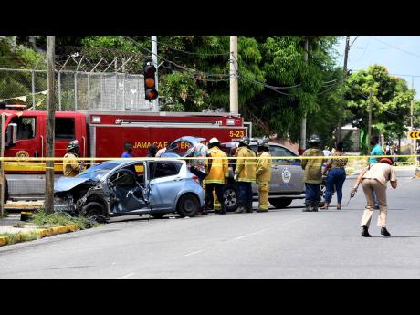 Credit: Ian Allen Members of the Jamaica Constabulary Force (JCF) process the crime scene, with assistance from the Jamaica Fire Brigade in searching the crashed motorcar, which was allegedly occupied by gunmen, who had engaged the police in a shoot-out. Two of the occupant
