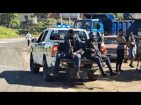 Security members sit on a Jamaica Constabulary Force pickup truck during an operation in Ellerslie Gardens in Spanish Town, St Catherine, on Friday, December 29, 2023.