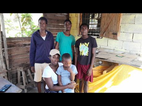 
Davianne McDermott sits with her son, five-year-old Domanique. Sharing in the moment are his rescuers (from left) Kenroy McKenzie, 17; Roshane Roberts, 15; and Tyrese Wright, 17.