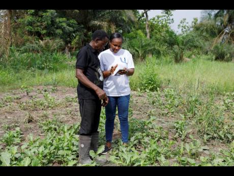 Rita Quansah, right, from Uniti Networks, shows farmer Cyril Fianyo, 64, how to navigate the farmers’ apps on his phone in Atabu, Hohoe, in Ghana’s Volta Region, Wednesday, April 18, 2024.
