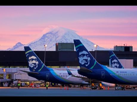 Alaska Airlines planes are shown parked at gates, with Mount Rainier in the background at sunrise, on March 1, 2021 at Seattle-Tacoma International Airport in Seattle.