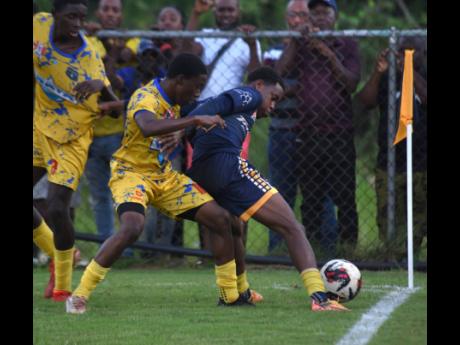 Munro College’s Antwone Smith (right) shields the ball from Clarendon College’s Daneil Clarke during their ISSA/WATA daCosta Cup round-of-16 clash at Munro College’s playfield yesterday.