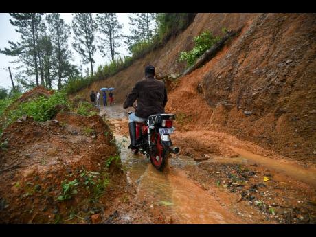 A motorist carefully navigates his way through a section of Mango Row Road in Cedar Grove, St Thomas, which was affected by a landslide during the passage of Tropical Storm Rafael.