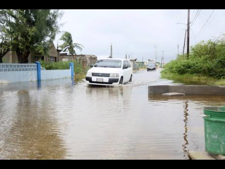 Motorists drive along a flooded roadway in Portland Cottage, Clarendon, because of rainfall associated with Tropical Storm Rafael on Tuesday.