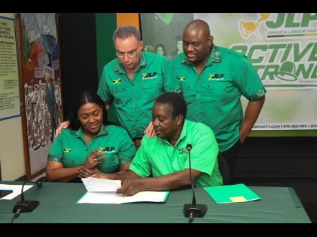 Daryl Vaz (standing left), Jamaica Labour Party (JLP) treasurer; Marlon Morgan (standing right), Communications Task Force member; Member of Parliament Kerensia Morrison (seated left); and JLP Chairman and Member of Parliament Robert Montague look over doc