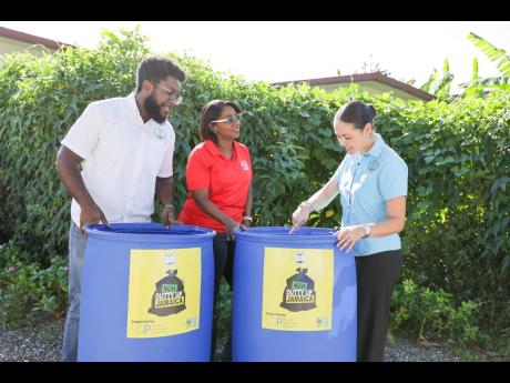 Yanique Forbes-Patrick (centre), vice-president, public affairs and communications at Scotiabank, listens keenly as Dr Theresa Rodriguez-Moodie (right), chief executive officer of the Jamaica Environment Trust (JET), shows off the barrels used as receptacl