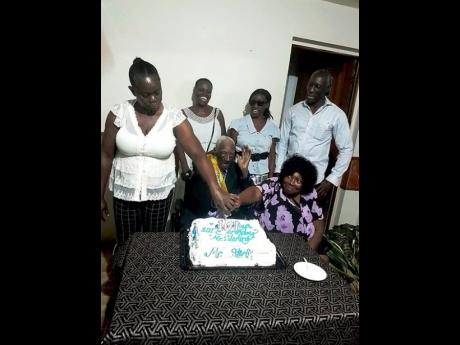 Ivan Sterling (centre, seated) and his wife Velma Sterling (seated, right) take part with some of their children in cutting his cake during his 101st birthday celebration at the Norwood Seventh-day Adventist Church in Norwood, St James, on January 12. Also