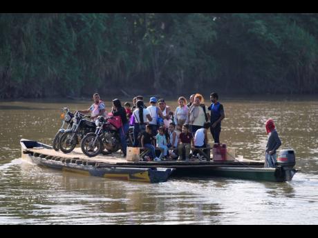 Residents cross a river to Venezuela from Colombia's Tibu, Tuesday, January 21, 2025, following guerrilla attacks that killed dozens and forced thousands to flee their homes in the Catatumbo region. (AP Photo/Fernando Vergara)