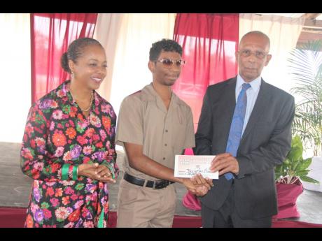 Marlene Malahoo-Forte, member of parliament for St James West Central, looks on as Herbert Morrison Technical High School student Nicholas Bicarie collects his science, technology, engineering, and mathematics (STEM) scholarship from retired educator Derri
