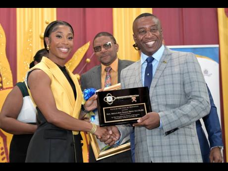 Mayor of Kingston Andrew Swaby (right) presents the Key to the City to Shelly-Ann Fraser-Pryce while Councillor Eugene Kelly looks on during a ceremony held at the Douglas Orane Auditorium on the campus of Wolmer’s Boys’ School in St Andrew yesterday.