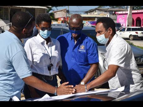 Credit: File Desmond McKenzie (centre), minister of local government and community development, is surrounded by a team of technical experts, examining the plans for the Negril Fruits and Vegetables market in Westmoreland in 2022. Others in photo from are Wray Mullings