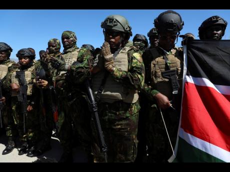 Credit: AP Odelyn Joseph Kenyan police, who are part of a UN-backed multinational force, pray on the tarmac after landing at the Toussaint Louverture International Airport in Port-au-Prince, Haiti, on February 6.
