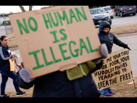 Credit: AP Supporters hold signs during a protective accompaniment vigil for people arriving at their immigration appointments outside of the US Immigration and Customs Enforcement office in Cedar Rapids, Iowa on February 4.