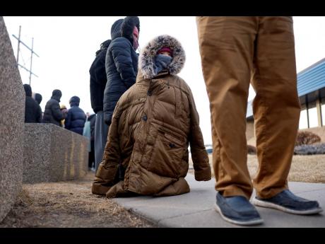 Credit: AP A child, bundled against the cold, stands in line to attend an immigration registration meeting outside of the US Immigration and Customs Enforcement office in Cedar Rapids, Iowa on February 4.