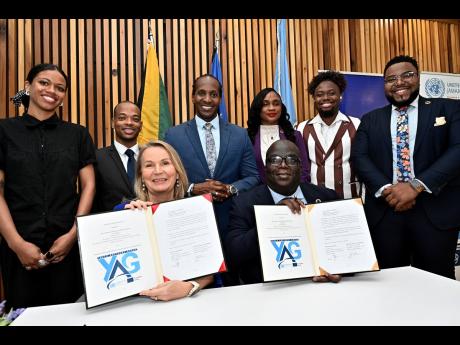 Dr. Erja Askola (left), ambassador of the European Union (EU) to Jamaica, and Dennis Zulu (right), United Nations (UN) resident coordinator, displaying the signed document at the launch ceremony of the UN/EU 
Youth Advisory Group (YAG) at the European Unio