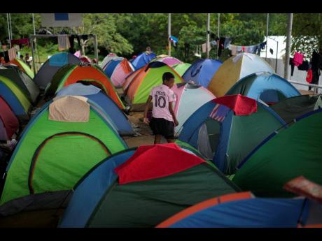Credit: Matias Delacroix FILE – A migrant who walked across the Darien Gap from Colombia stands amid tents at a temporary camp in Lajas Blancas, Panama, last June.
