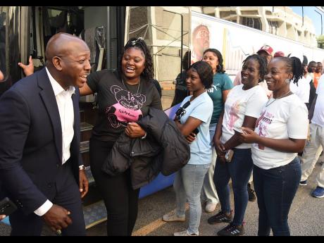 Credit: Ian Allen Pearnel Charles Jr (left), Minister of Labour and Social Security, enjoys a moment with some of the persons departing for work in Canada.