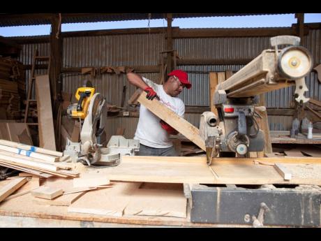 Ex-migrant Eduardo Jimenez saws wood in a carpentry workshop in Cajola, Guatemala, November 29, 2021. Jimenez’s project creates doors and woodwork for homes paid for with money sent home from the US. 