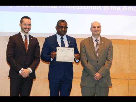 Credit: Derrick Scott Acting Senior Superintendent of Police, Victor Barrett of the Counter-Terrorism and Organised Crime Investigation Branch (left), displays his certificate after graduating from the two-week Caribbean Security and Defence course. He is flanked by Dean of the