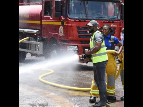Montego Bay Mayor Richard Vernon and Ramona Shaw, of the Jamaica Fire Brigade, participate in cleaning activities at the Charles Gordon Market in Montego Bay, St James, on Labour Day. The cleaning of the Charles Gordon Market was this year’s Labour Day p