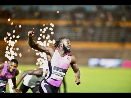 Credit: Matthew McKoy Rasheed Broadbell raises his hand skyward after pipping the United States’ Trey Cunningham to the tape in the men’s 110-metre hurdles at the Racers Grand Prix inside the National Stadium on Saturday.