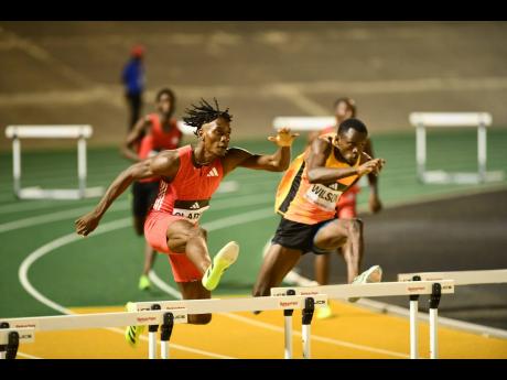 Credit: Matthew McKoy Roshawn Clarke (left) and Assinie Wilson go toe to toe over a hurdle during the men's 400-metre hurdles at the Racers Grand Prix at the National Stadium on Saturday.