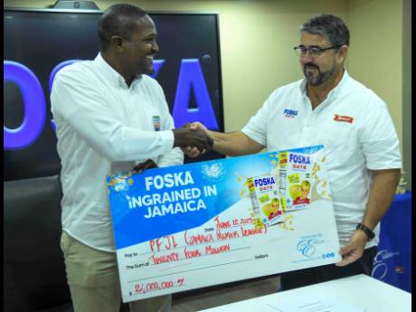 Credit: Antoine Lodge Chris Ramson, managing director of Caribbean Foods (right), presents a cheque to Owen Hill, CEO of Professional Football Jamaica Limited, at Chas. E. Ramson Ltd’s office yesterday.