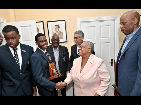 Credit: Rudolph Brown/Photographer Marlene Street Forrest (second right), managing director of the Jamaica Stock Exchange; greets Justin Phinn (second left), Jamaica College (JC) Stock Market Club team captain, while looking on from (third left) are Wayne Robinson, principal of JC; Richard