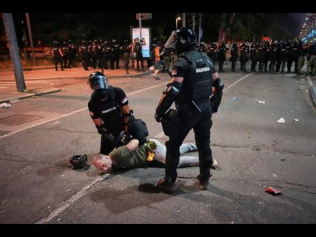Riot police detain a man after charging protesters at the end of an anti-government rally pressing for an early election in Belgrade, Serbia.