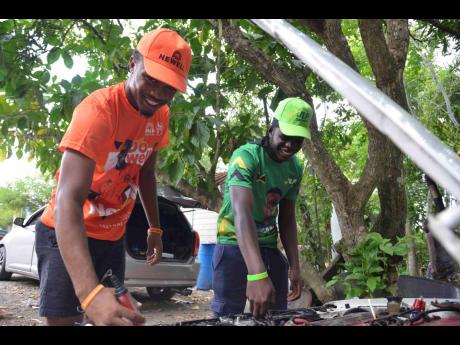 Malique Wellington (left), a People’s National Party supporter, is assisted by his friend, 16-year-old Dwayne Young, a Jamaica Labour Party supporter, with fixing his vehicle after the close of polls on Wednesday.